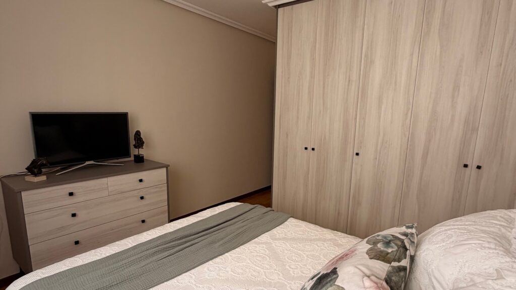 Dormitorio con armario a medida de puertas correderas en tono madera clara