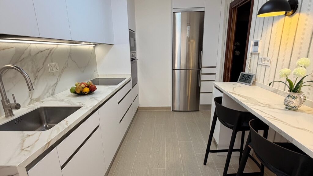Cocina blanca Blanco Pure con encimera porcelánica Neolith Calacatta Roma y barra